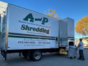 A person loading a secure collection container into an A and P mobile shredding truck.