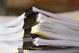 Large stack of paper documents bound with black binder clips.